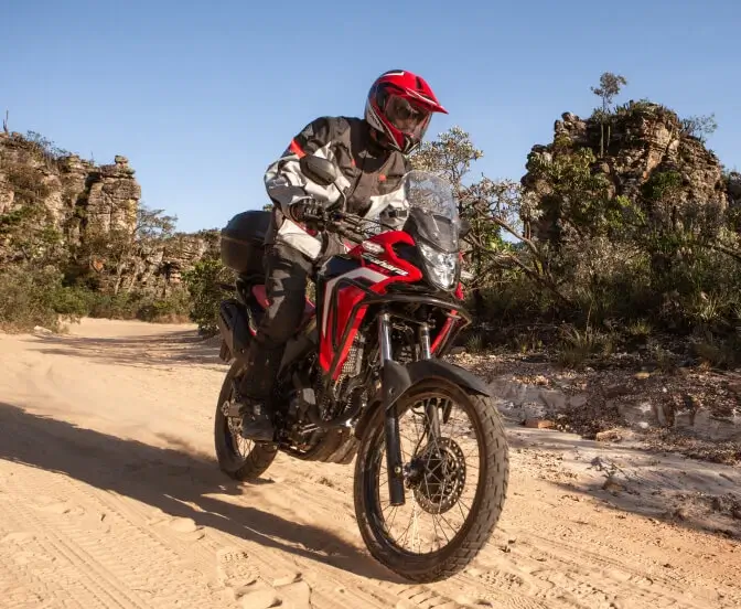 piloto-em-moto-honda-sahara-300-vermelha-em-estrada-de-areia